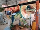 Дети едут на динозавре тематического парка для оборудования развлечений